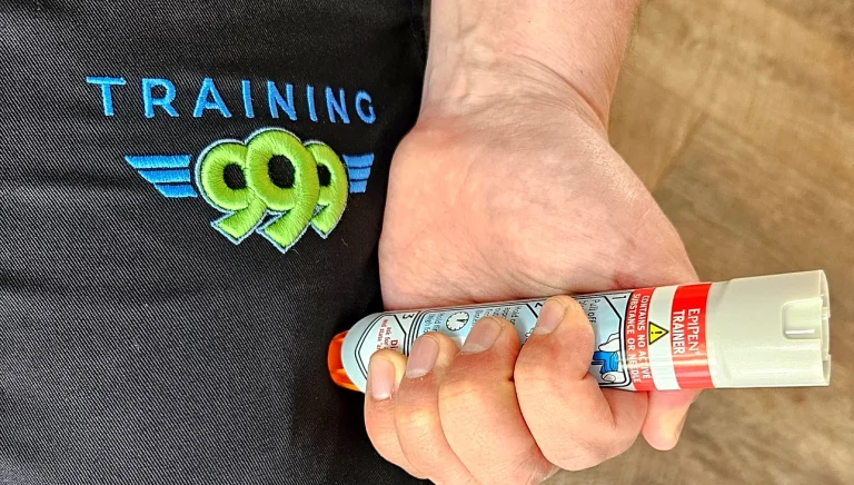 Training 999 instructor holding EpiPen trainer device during anaphylaxis training for school staff