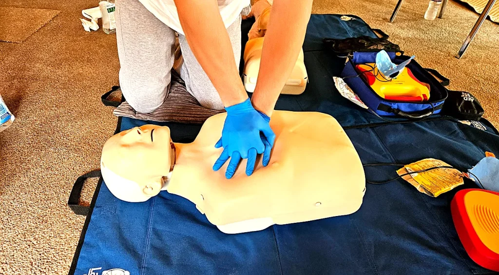 First aid training Felixstowe – learner practising CPR chest compressions on mannequin during on-site workplace course