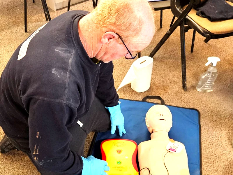 AED defibrillator training Ipswich – learner practising with training AED and CPR mannequin during on-site first aid course