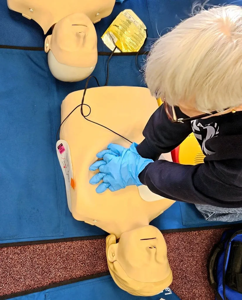 Delegate practising CPR chest compressions on a training manikin with AED equipment during an Emergency First Aid at Work course in Soham, Cambridgeshire, delivered by Training 999